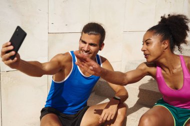 Genç ve zinde bir çift gün boyunca merdiven boşluğunda otururken selfie çekiyorlar.