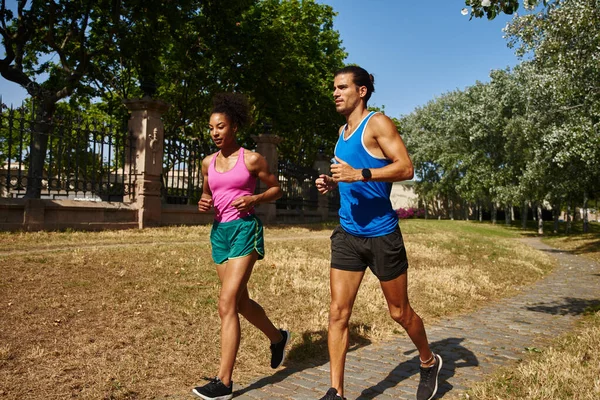 在阳光灿烂的日子里 一对年轻夫妇穿着运动服一起在室外跑步 — 图库照片