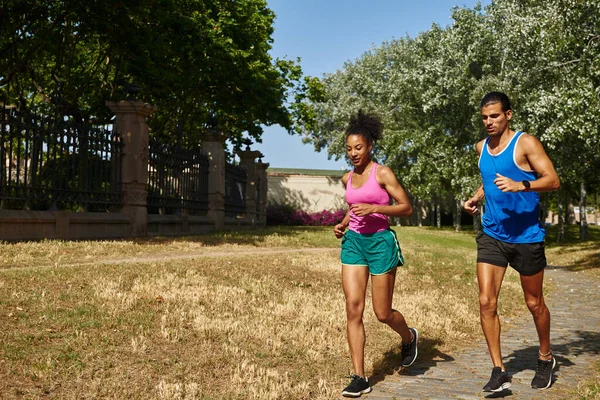 活跃的年轻夫妇白天穿着运动服一起在室外跑步 — 图库照片