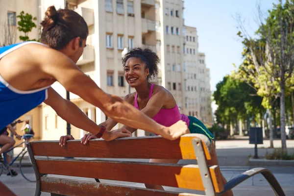 陽気な若いカップルは 市内の屋外でのワークアウトセッション中にベンチで演習を行う — ストック写真