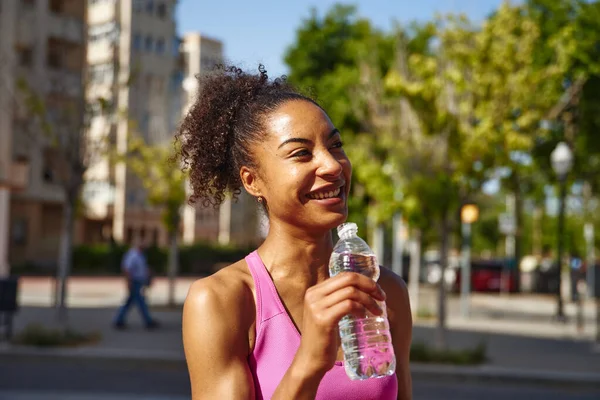 市内の屋外で働くことから休憩を取りながら 若い女性が水のボトルを保持笑顔 — ストック写真