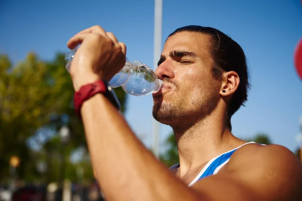 昼間に屋外で働くことから休憩を取りながら ボトルから水を飲む運動青年 — ストック写真