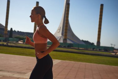 Güzel bir kadın güneşli bir sokakta egzersiz yapıyor ve pratik yapıyor.