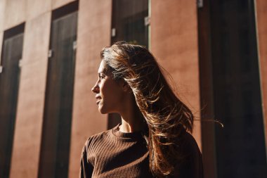 Kendine güvenen genç ve güzel bir iş kadını sokakta durup düşünüyor.