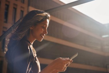 Tablet kullanarak güneşin altında gülümseyen genç iş kadını.
