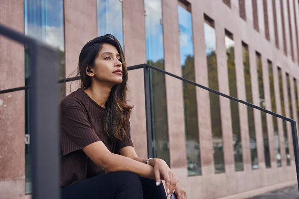 Beautiful businesswoman sitting with hand on knee contemplating