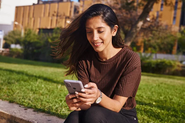 Genç Güzel Bir Kadını Parkta Cep Telefonuyla Oturuyor Çalışıyor — Stok fotoğraf