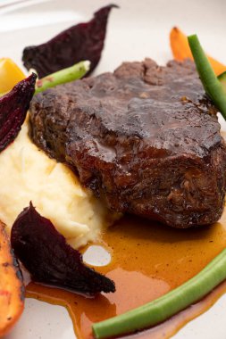 Portakal sosu, sebze ve patates püresiyle pişirilmiş kalın sığır eti.
