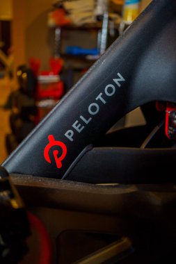 New York - Circa 2022: Peloton logo on the base of flagship stationary exercise bike setup for fitness riding use clipart