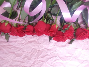 On a pink background, a bouquet of red roses, and a plate for the inscription