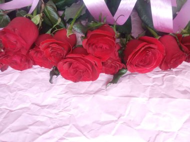 On a pink background, a bouquet of red roses, and a plate for the inscription