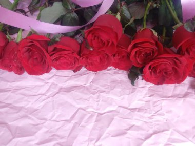 On a pink background, a bouquet of red roses, and a plate for the inscription
