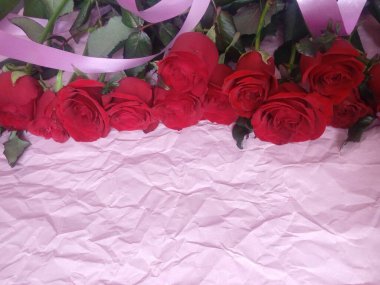 On a pink background, a bouquet of red roses, and a plate for the inscription
