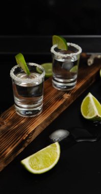 İki yığın taze limon dilimleri ve siyah arka planda izole edilmiş ahşap tahta üzerine tuz.