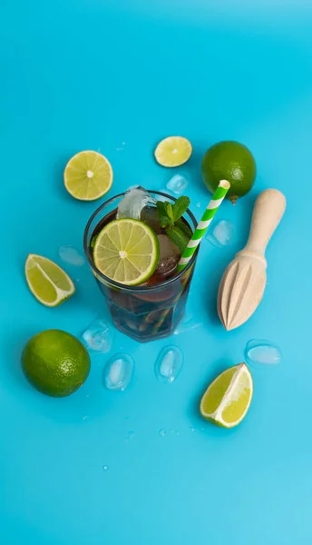 Yaz soğuyan rom, buz ve olgun limonla kokteyl. Temiz mavi bir arka planda dilimlenmiş.