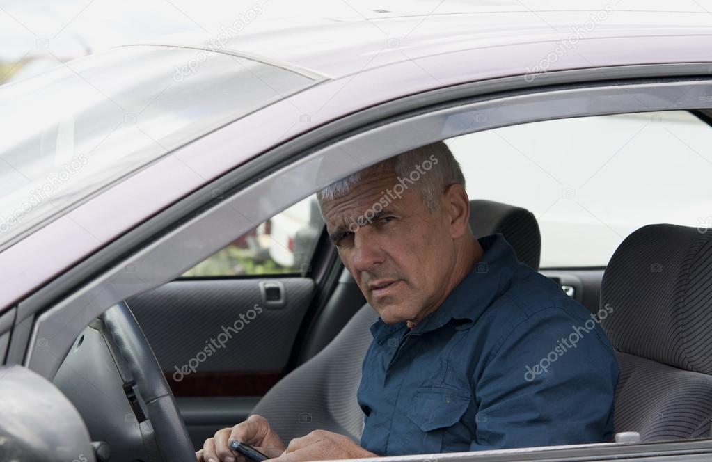 Elderly man in car with phone
