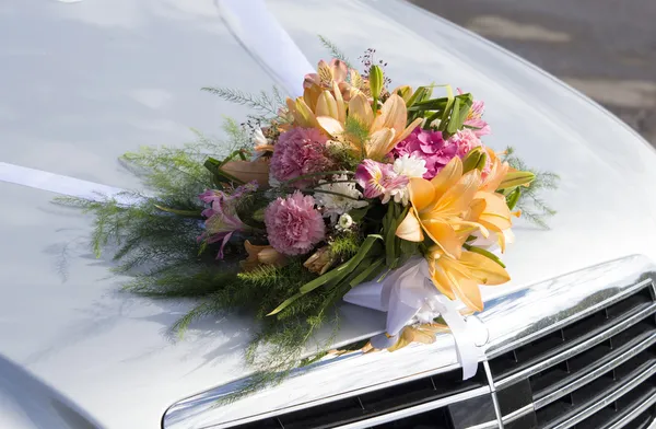 Wedding bouquet on a front hood of a car — Stock Photo, Image