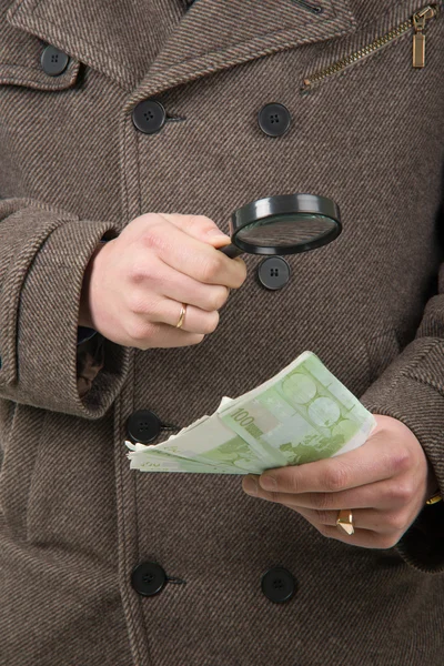 Hand mit Euro-Banknoten und Lupe — Stockfoto