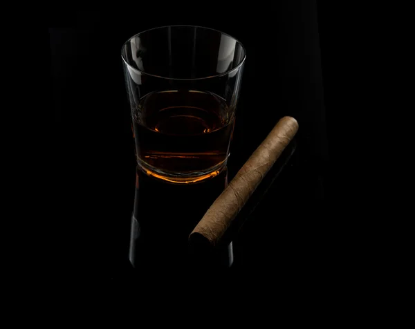 Un bicchiere con cognac e sigaro isolato su nero — Foto Stock