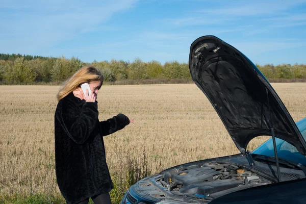 Hermosa chica rubia llamando al teléfono celular cerca de su coche roto — Foto de Stock