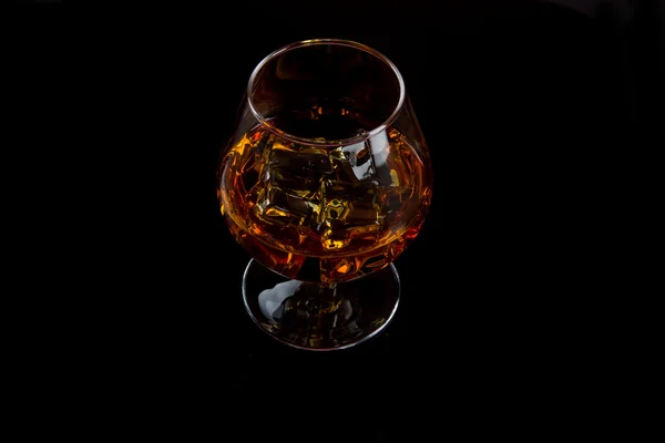 Glass of whiskey with ice on black — Stock Photo, Image