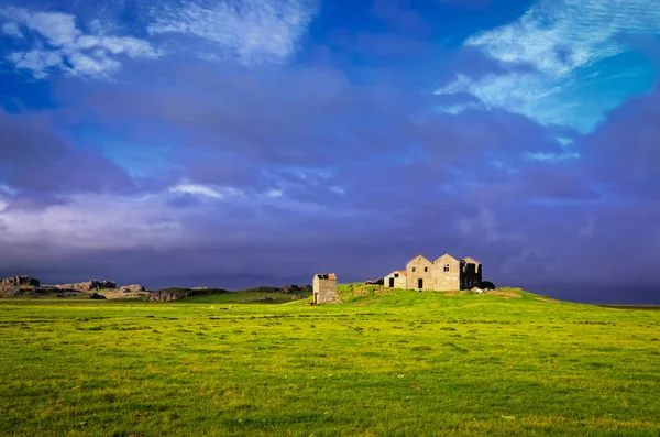Stary zardzewiały dom i stodoła w zielony łąka i burzliwy chmury — Zdjęcie stockowe