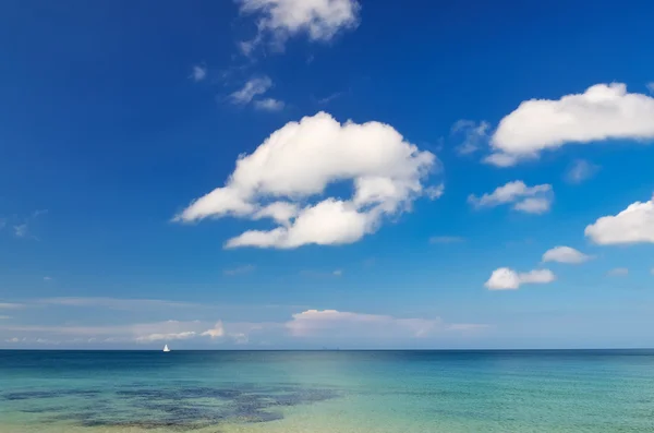 Paisaje oceánico con cielo azul nublado y velero pequeño — Foto de Stock