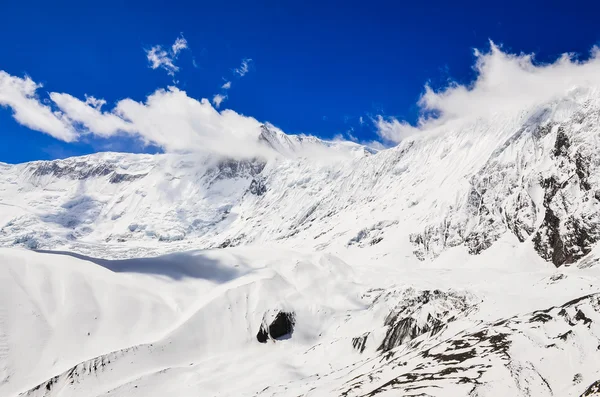 Pico de montanha de neve com nuvens e céu azul — Fotografia de Stock