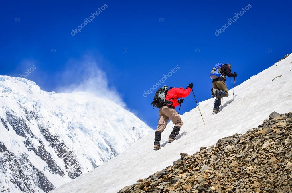 Two mountain trekkers on snow with peaks background