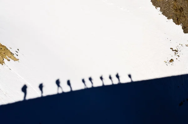 Las sombras del grupo de los excursionistas montañosos sobre la nieve —  Fotos de Stock