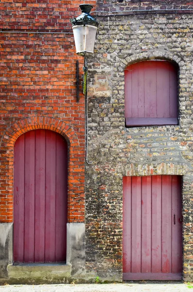 Oude vintage bakstenen muur met rode houten deuren en ramen — Stockfoto