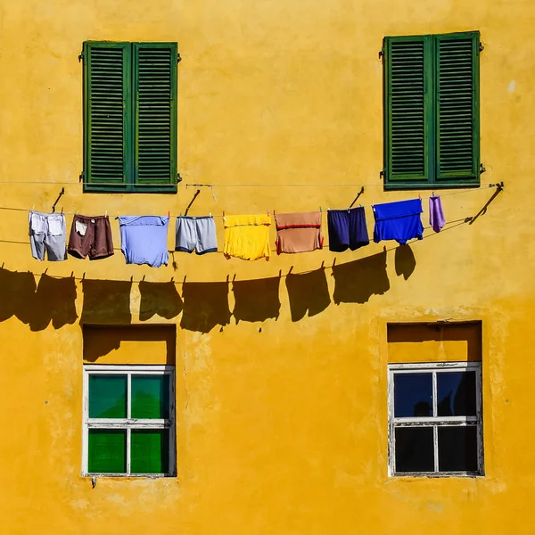 Detaliu de pereți galbeni colorați, ferestre și haine — Fotografie, imagine de stoc