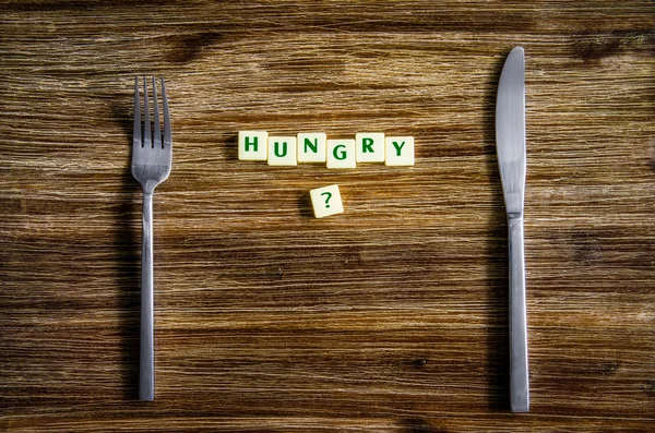 Příbory sada na dřevěný stůl s otázkou hlad — Stock fotografie