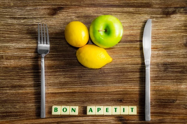 Lemons and apple on wooden vintage table with silverware — Stock Photo, Image