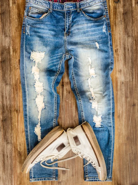 Detail of vintage weathered jeans and shoes on wood texture — Stock Photo, Image