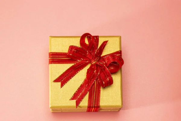 Karácsonyi Arany Ajándékdobozok Piros Szalag Feküdt Asztalon Rózsaszín Háttér Előnézet — Stock Fotó