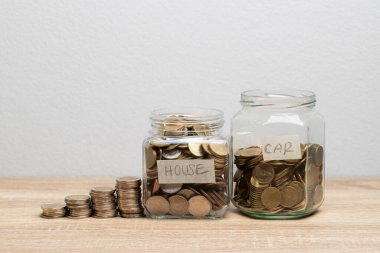 Para yığını ve finansal konsept için kopyalama alanı olan kahverengi masada para biriktirmek için cam kavanoza para koy.