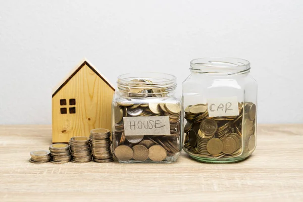 お金のスタックと木製の家と茶色のテーブルのガラス瓶のコイン 金融の概念のためのスペースをコピー — ストック写真