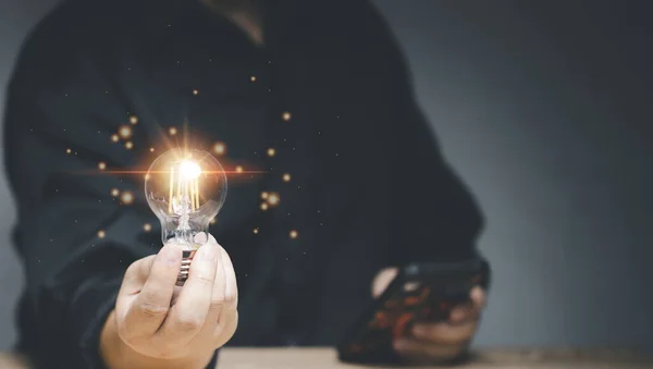 Idea innovation and inspiration concept. Hand of man holding illuminated light bulb, concept creativity with bulbs that shine glitter. Inspiration of ideas for sustainable business development.