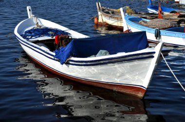 Balıkçı tekneleri, beyaz ve mavi küçük ahşap balıkçı tekneleri güneşli bir günde Ege Denizi 'nde demirleyip yüzüyorlar. Seçici odak.
