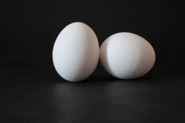 Eggs, stüdyo fotoğrafındaki çiğ tavuk yumurtalarının detaylı görüntüsünü kapat. Koyu arkaplanda izole edilmiş, seçici odak.