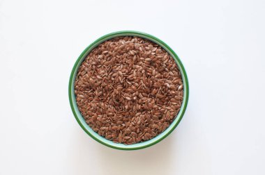 Top view of organic and healthy raw flaxseeds or linseeds in green bowl.  Natural, proper nutrition, superfood isolated on white background, selective focus.