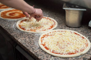 Aşçı mutfakta, pizzanın malzemelerini koyuyor. Pizza konsepti. Gıda üretimi ve teslimatı.
