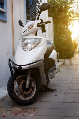 Eski bir Avrupa caddesinde beyaz bir motosiklet duruyor..