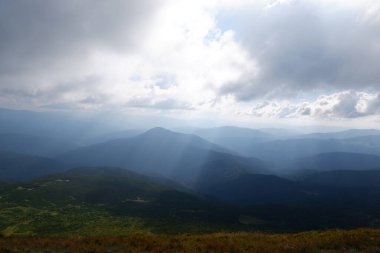 Muhteşem dağların ve güneş ışınlarının gölgeli bulutların arasından doğuşunun güzel bir manzarası..