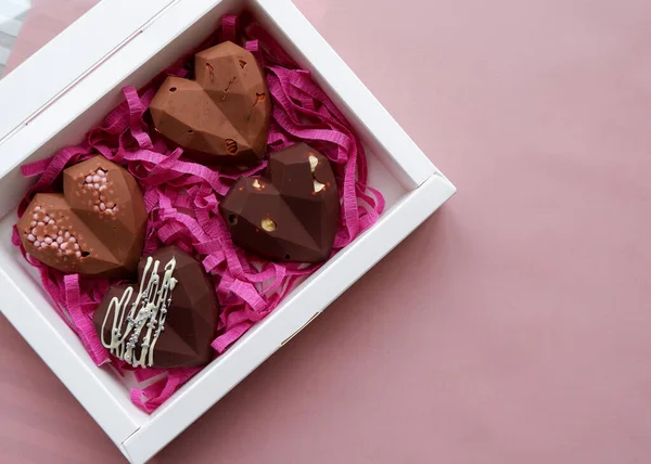 Handmade chocolates in a white gift box. Heart shaped sweets with milk chocolate with nuts.