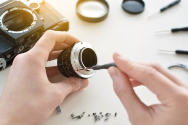 Mühendisi-teknisyeni optik denetler ve bakım ve temizlik kamera kırık vintage objektifi ile taşıyor. İşyeri ve mühendis elleri Üstten Görünüm.