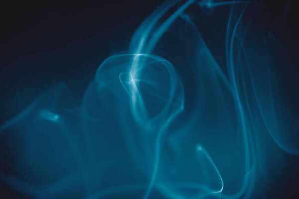 Smoke clouds swirling in blue light against a dark background.