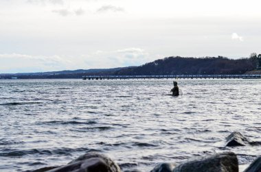 Adam Baltık Denizi 'nin kayalık kıyısında Orlowo, Gdynia, Polonya' da balık tutuyor.