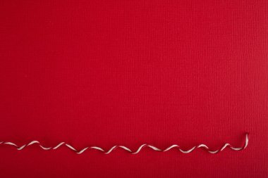 Kırmızı kağıdın ve çizgili kıvrımlı dekoratif ipin soyut Noel arkaplanı, metin içeriği için kopyalama alanı